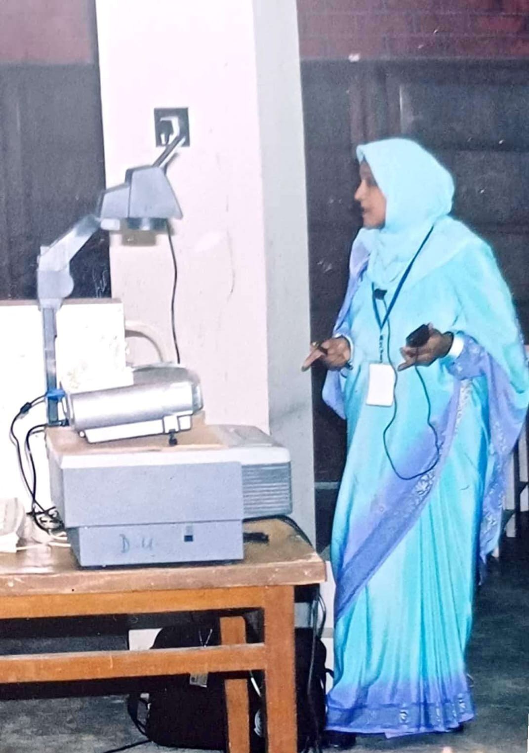 Dr. Nilufar Nahar lecturing beside an overhead projector at the University of Dhaka